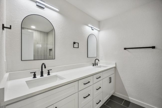 Full bathroom with tile patterned flooring, double vanity, a textured wall, and baseboards | Image 30