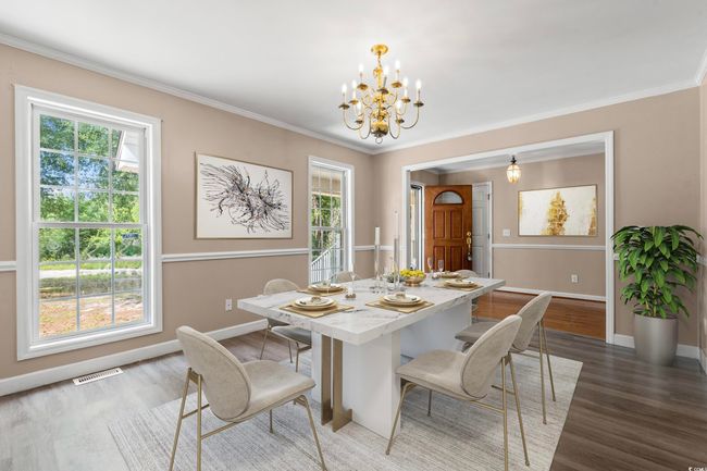 Dining space with a chandelier, wood finished floors, healthy amount of natural light, and ornamental molding | Image 9