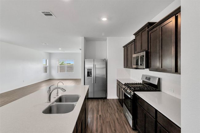 Kitchen featuring appliances with stainless steel finishes, dark brown cabinets, light countertops, dark wood-style floors, and recessed lighting | Image 14