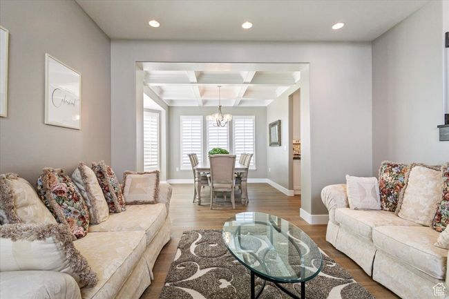 Living room featuring coffered ceiling, a chandelier, beam ceiling, wood finished floors, and recessed lighting | Image 7