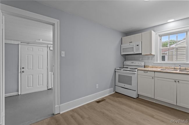 Kitchen featuring white appliances, light wood-style flooring, a sink, baseboards, and visible vents | Image 14