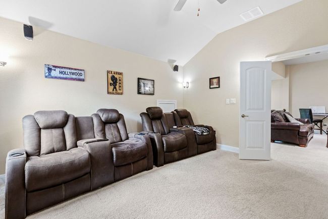 Carpeted home theater with lofted ceiling, ceiling fan, and baseboards | Image 25