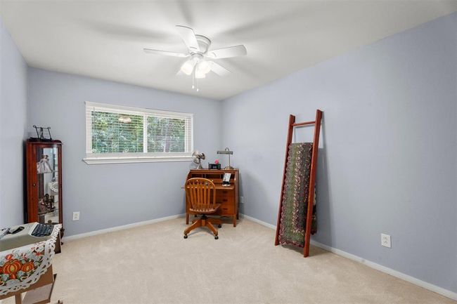 This spacious bedroom features soft carpet, and a ceiling fan. | Image 19
