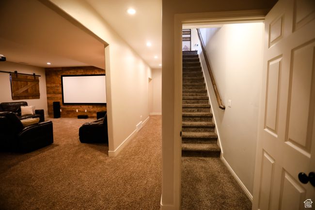 Carpeted home theater room with recessed lighting, a barn door, and baseboards | Image 58