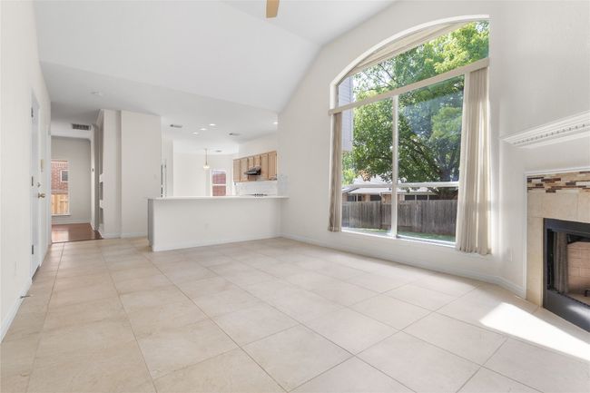 Unfurnished living room with lofted ceiling, a tile fireplace, plenty of natural light, and light tile patterned flooring | Image 9