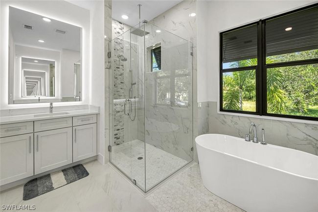 Master bath shower featuring a frameless glass enclosure with rain shower, fixed shower head and handheld shower fixtures. Custom tile work, soap/shampoo niches and all LED down lighting. | Image 11