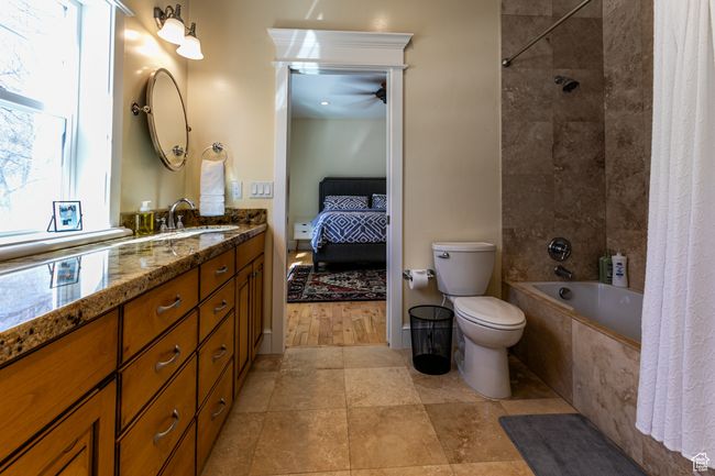 Bathroom with connected bathroom, toilet, a ceiling fan, vanity, and tiled shower / bath | Image 17