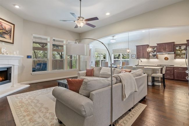 With custom window treatments throughout, the spacious family room features high ceilings, fireplace, hardwood floors, and large windows overlooking the backyard retreat | Image 13
