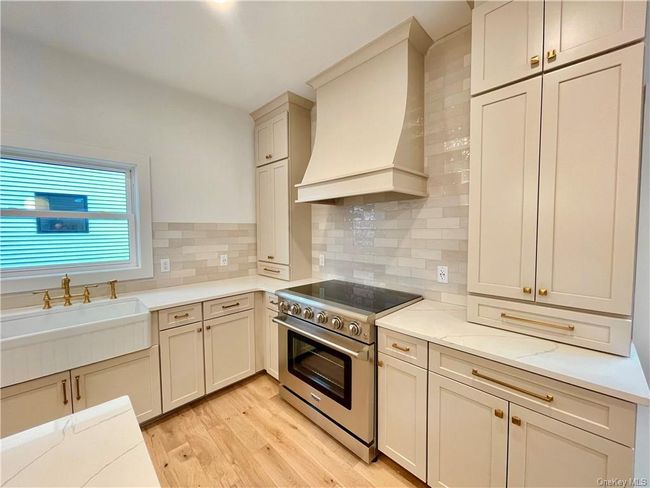 Example of the work we do. Not this house. Kitchen with light hardwood / wood-style flooring, tasteful backsplash, light stone counters, premium range hood, and high end stove | Image 8