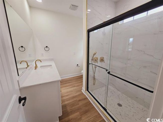 Bathroom featuring toilet, a marble finish shower, wood finished floors, and vanity | Image 30