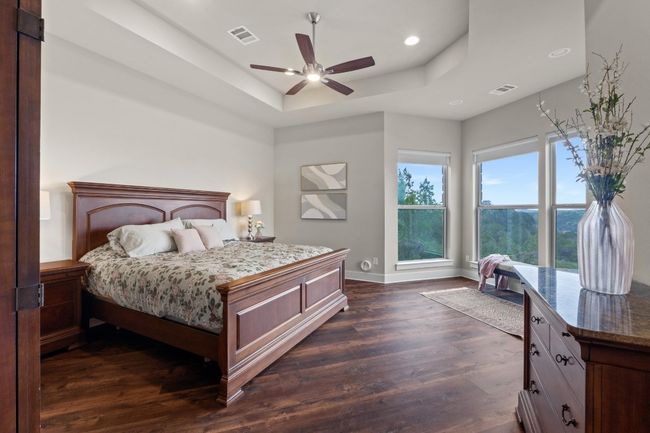 Bedroom featuring dark wood-style floors, baseboards, a tray ceiling, and visible vents | Image 16