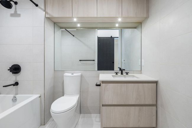 Bathroom with bathtub / shower combination, toilet, vanity, and tile walls | Image 18