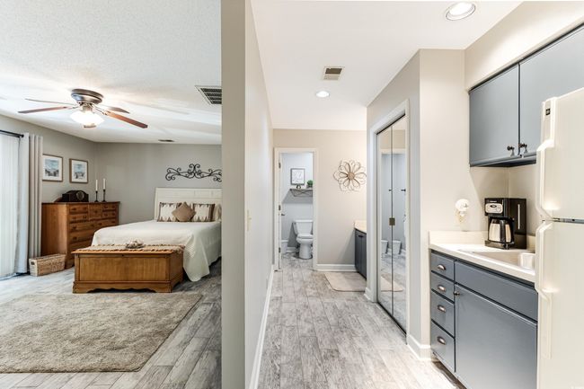 Bedroom with light wood-type flooring, freestanding refrigerator, visible vents, and connected bathroom | Image 14