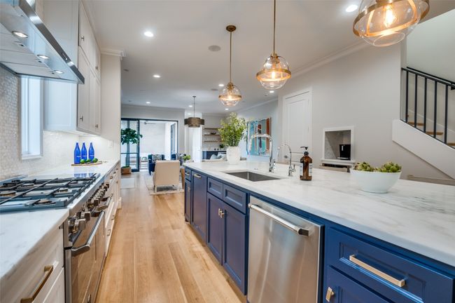 Kitchen with white cabinetry, stainless steel appliances, blue cabinets, exhaust hood, and a sink | Image 12
