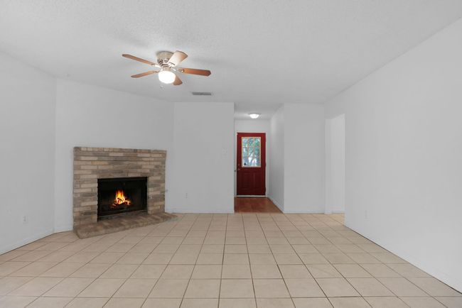 Unfurnished living room featuring ceiling fan and a fireplace | Image 9