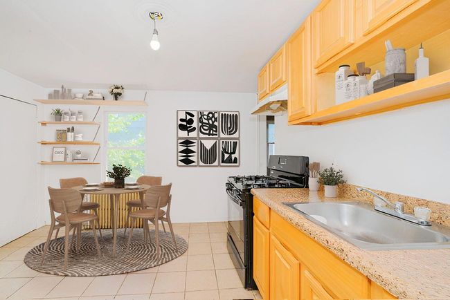 Kitchen with gas stove, open shelves, under cabinet range hood, light brown cabinetry, and light tile patterned flooring | Image 11