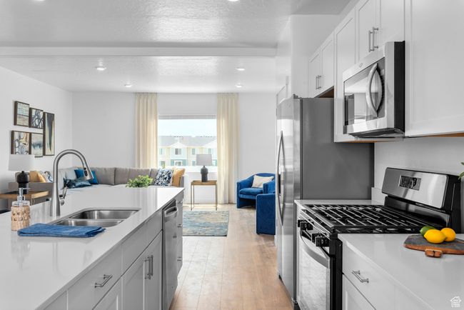 Kitchen featuring appliances with stainless steel finishes, open floor plan, light countertops, light wood-style floors, and recessed lighting | Image 8