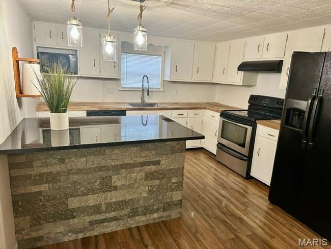 Kitchen featuring white cabinetry, black fridge, stainless steel electric stove, and sink | Image 18
