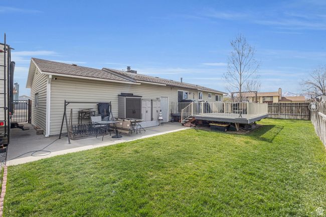Rear view of house with a fenced backyard, a lawn, and a patio area | Image 21