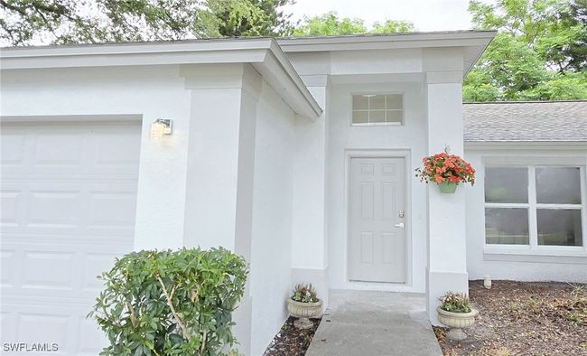 Doorway to property featuring stucco siding and an attached garage | Image 40