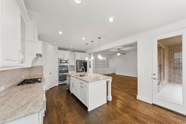 Kitchen with a sink, stainless steel appliances, a ceiling fan, white cabinetry, and tasteful backsplash | Image 9
