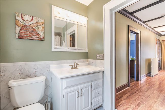 Bathroom with wood finished floors, wainscoting, vanity, tile walls, and toilet | Image 26