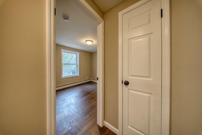 Hall featuring a baseboard radiator, baseboards, and dark wood-style flooring | Image 20