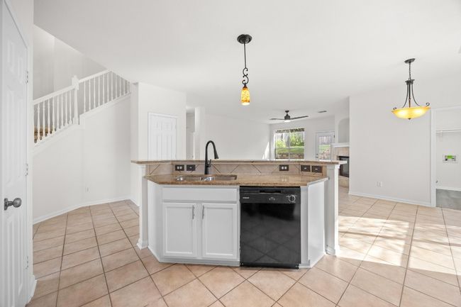 Kitchen featuring dishwasher, light tile patterned floors, a ceiling fan, and hanging light fixtures | Image 14