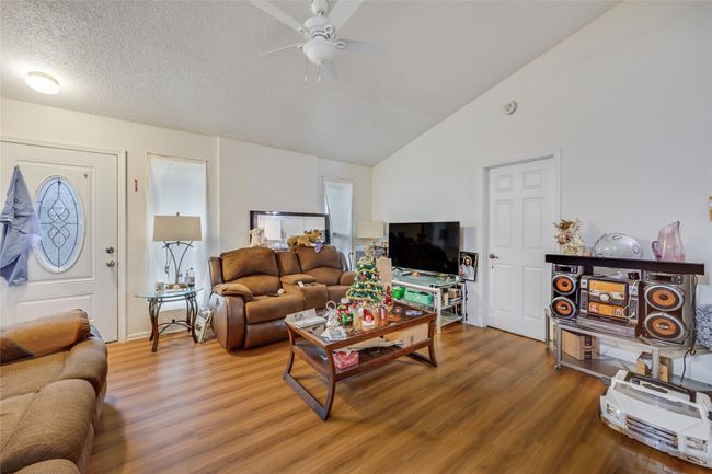Unit A Living room featuring ceiling fan, vaulted ceiling, a textured ceiling, and hardwood / wood-style floors | Image 28