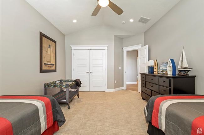 Bedroom featuring light colored carpet, vaulted ceiling, ceiling fan, a closet, and baseboards | Image 22