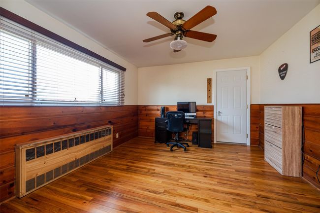 Home office with ceiling fan, wainscoting, light wood-style floors, and radiator heating unit | Image 9