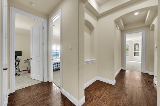 Hall with dark wood-style flooring, a desk, arched walkways, and a tray ceiling | Image 22