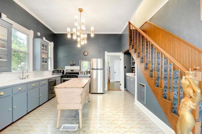 Kitchen with stainless steel appliances, light floors, a chandelier, light countertops, and crown molding | Image 12
