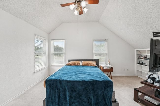 Bedroom featuring carpet flooring, a textured ceiling, multiple windows, a ceiling fan, and lofted ceiling | Image 23