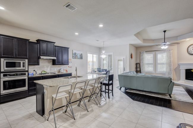 Kitchen with stainless steel appliances, a sink, open floor plan, a breakfast bar, and a center island with sink | Image 7