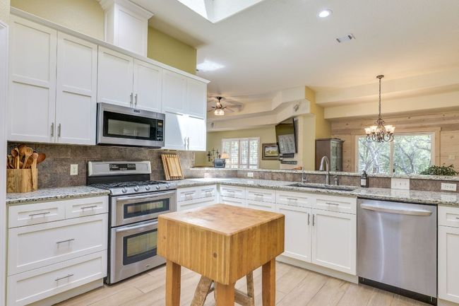Kitchen with appliances with stainless steel finishes, tasteful backsplash, white cabinetry, hanging light fixtures, and recessed lighting | Image 19