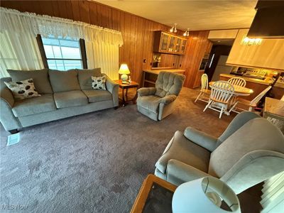 Living room with wooden walls and carpet floors | Image 3