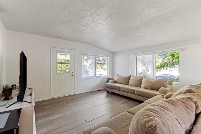 Living area with wood-type flooring, a textured ceiling, and lofted ceiling | Image 11