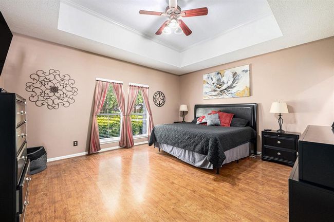 Primary retreat boasts a beautiful tray ceiling, crown molding, ceiling fan and an en-suite bathroom. | Image 12
