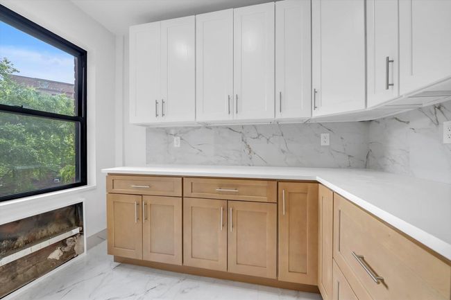 Kitchen with light countertops, tasteful backsplash, and white cabinets | Image 8
