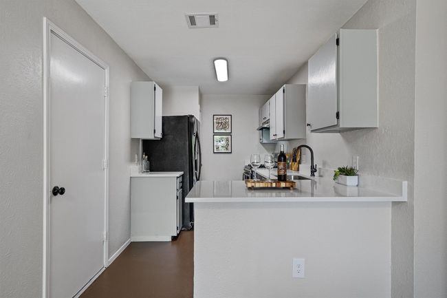 Kitchen with light countertops, freestanding refrigerator, a peninsula, finished concrete floors, and range | Image 8