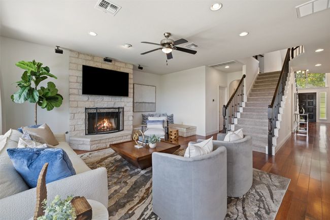 Living room featuring stairway, recessed lighting, dark wood-style floors, a fireplace, and ceiling fan | Image 21