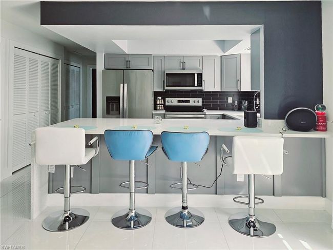 Kitchen with a peninsula, light countertops, stainless steel appliances, and a breakfast bar | Image 14