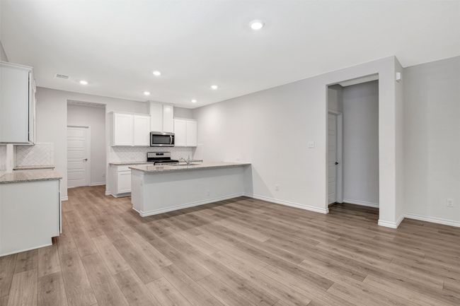 Kitchen with appliances with stainless steel finishes, tasteful backsplash, a peninsula, light wood-type flooring, and recessed lighting | Image 11