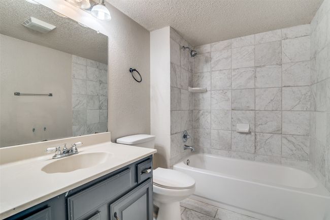 Full bath with a textured ceiling, vanity, shower combination, and a textured wall | Image 23