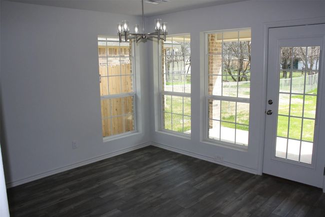 Unfurnished dining area with a chandelier, dark wood-style flooring, and plenty of natural light | Image 5