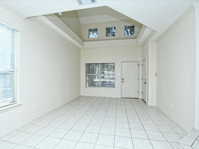 Unfurnished room with a high ceiling, light tile patterned flooring, and visible vents | Image 4