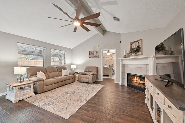 The inviting family room is anchored by large windows with backyard views and a cozy fireplace with decorative molding—blending warmth and style in this open-concept gathering space. | Image 10
