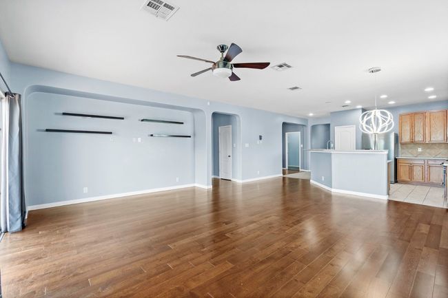 Unfurnished living room featuring ceiling fan, recessed lighting, arched walkways, and wood finished floors | Image 12