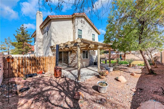 Back of house featuring a patio, a fenced backyard, a pergola, a chimney, and stucco siding | Image 40